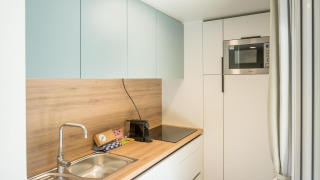 Cocina luminosa y moderna en un lodge con encimera de madera, fregadero, vitrocerámica y microondas.