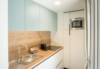 Moderne, lichte lodgekeuken met houten werkblad, spoelbak, kookplaat en ingebouwde magnetron.