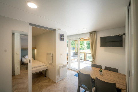 Lyst og moderne opholdsrum i Lodgep - IEPER, Urban-Gardens Ieper, Belgien, med spisebord, soveområde og udsigt til haven.
