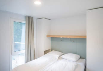 Luminoso dormitorio moderno en un lodge con cama doble, ropa de cama blanca y luz natural.