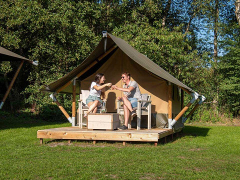 Zwei Personen genießen Getränke vor einem Glampingtent XS - IEPER auf Urban-Gardens Ieper in Belgien.