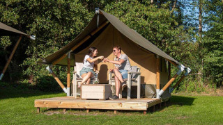 To personer nyder drikkevarer foran et Glampingtent XS - IEPER ved Urban-Gardens Ieper i Belgien.