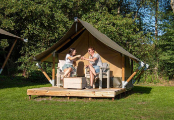 Dos personas disfrutan bebidas frente a una Glampingtent XS - IEPER en Urban-Gardens Ieper, Bélgica.