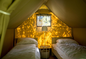 Interior of safari tent with two single beds and lamp at Glampingtent XS - IEPER, Urban-Gardens Ieper, Belgium.