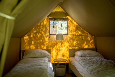 Interno di tenda safari con due letti singoli e lampada a Glampingtent XS - IEPER, Urban-Gardens Ieper, Belgio.