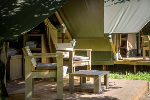 Wooden patio chairs and table outside a safari glamping tent at Urban-Gardens Ieper in Belgium.