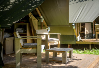 Wooden patio chairs and table outside a safari glamping tent at Urban-Gardens Ieper in Belgium.