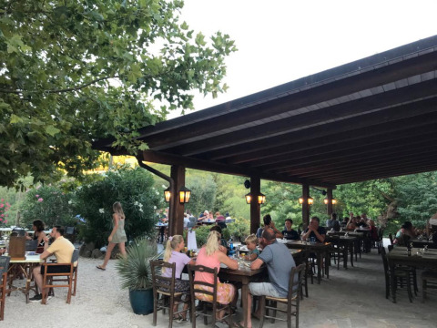 Udendørs spisning på Camping Podere sei Poorte med gæster under en overdækket terrasse i Marche, Italien.