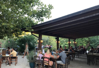 Gäste essen draußen auf der überdachten Terrasse im Camping Podere sei Poorte im ländlichen Marche, Italien.