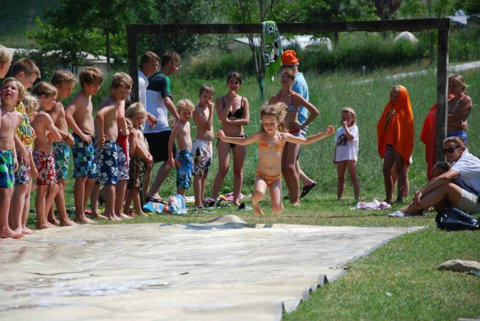 Niños juegan en un tobogán de agua al aire libre en Camping Podere sei Poorte, un parque en Marche, Italia.