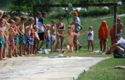 Børn leger på en vandrutchebane udendørs i solskin på Camping Podere sei Poorte i Marche, Italien.