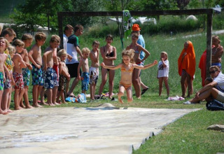 Bambini giocano sullo scivolo d'acqua all'aperto al Camping Podere sei Poorte, un parco vacanze nelle Marche.