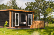Panorama lodge med wellness og udendørs badekar på Vakantiepark Hölte, omkranset af grøn natur i Holland.