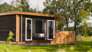 Casa Panorama con wellness y jacuzzi exterior en Vakantiepark Hölte, Países Bajos, rodeada de naturaleza verde.