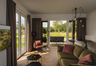 Helles Wohnzimmer der Panorama Lodge am Vakantiepark Hölte, modern eingerichtet mit Blick ins Grüne.