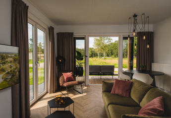 Lichte woonkamer in de Panorama Lodge van Vakantiepark Hölte, moderne stijl en uitzicht op natuur.