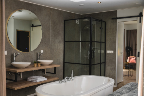 Modern bathroom at Panorama lodge, featuring a freestanding bathtub, twin sinks, and glass shower.