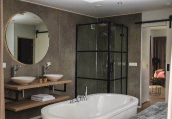 Moderne badkamer in Panorama lodge met vrijstaand bad, dubbele wastafels en glazen douche.
