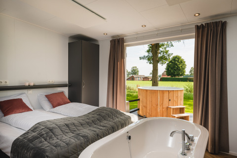 Panorama lodge con zona wellness, bañera interior y jacuzzi exterior en Vakantiepark Hölte, Países Bajos.