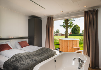 Panorama lodge met wellness, bad in de kamer en een buiten hot tub bij Vakantiepark Hölte, Nederland.