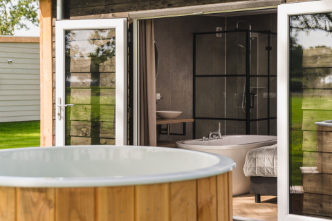 Außen-Whirlpool und offene Tür zur Panorama Lodge mit Wellness im Vakantiepark Hölte, Niederlande.