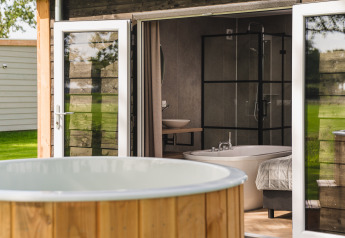 Vasca idromassaggio esterna e porte aperte verso la Panorama lodge al Vakantiepark Hölte, Olanda.