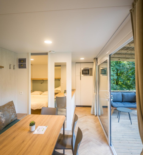 Indvendigt billede af en moderne lodge med spisebord, soveværelse og terrasse i Urban-Gardens Ieper, Belgien.