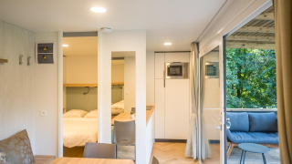 Indvendigt billede af en moderne lodge med spisebord, soveværelse og terrasse i Urban-Gardens Ieper, Belgien.