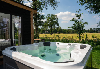 Jacuzzi buiten aan de Panorama Lodge met zicht op velden bij Vakantiepark Hölte in Nederland.