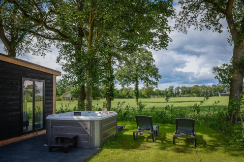 Outdoor wellness area with jacuzzi and lounge chairs at Panorama Lodge, Vakantiepark Hölte, Netherlands.