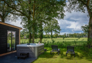 Area benessere esterna con jacuzzi e sedie a sdraio presso Panorama Lodge, Vakantiepark Hölte, Olanda.