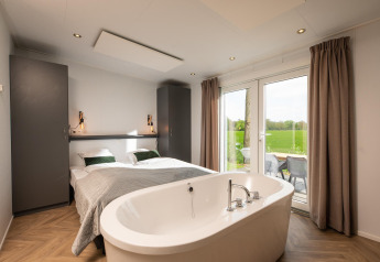 Dormitorio moderno en Panorama lodge con cama doble y jacuzzi en Vakantiepark Hölte, Países Bajos.