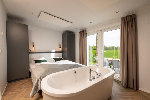 Moderne slaapkamer in Panorama lodge met tweepersoonsbed en jacuzzi bij Vakantiepark Hölte, Nederland.