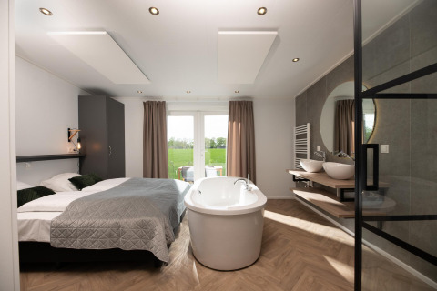 Modern panorama lodge tiny house with freestanding bathtub, double bed, and wellness at Vakantiepark Hölte, Netherlands.