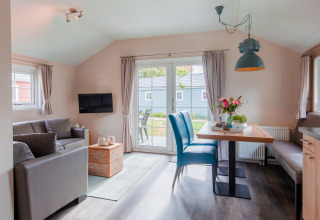 Bright, modern lodge living and dining area with large windows at Vakantiepark Leukermeer, Netherlands.