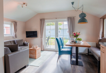 Lichte, moderne lodge woonkamer en eetruimte met grote ramen bij Vakantiepark Leukermeer, Nederland.
