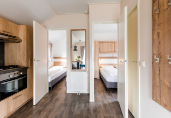 Moderne lodge med åbne døre til soveværelser, køkken og trægulv i Vakantiepark Leukermeer, Nederlandene.