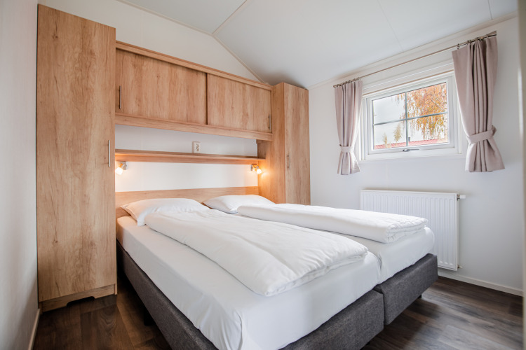 Dormitorio moderno en una cabaña de Vakantiepark Leukermeer, Países Bajos, con cama doble y armarios de madera.