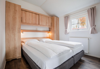 Moderne slaapkamer in een lodge op Vakantiepark Leukermeer, Nederland, met dubbel bed en houten kasten.