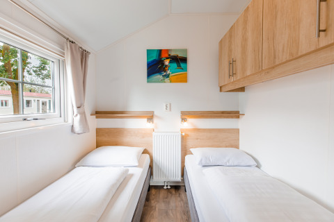 Twee eenpersoonsbedden met wit beddengoed in een lichte kamer van de Lodge op Vakantiepark Leukermeer, Nederland.