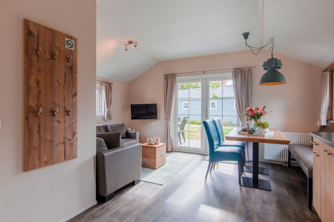 Sala luminosa de la cabaña con muebles modernos y mesa de comedor en Lodge en Vakantiepark Leukermeer, Países Bajos.