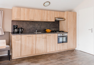Modern wood-finished kitchen in Lodge at Vakantiepark Leukermeer, Netherlands, featuring oven and appliances.