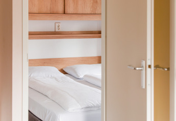 Vue sur une chambre lumineuse à la Lodge du Vakantiepark Leukermeer aux Pays-Bas avec lit double.