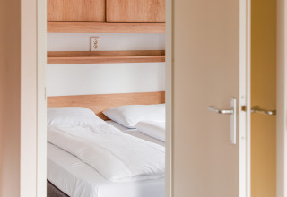 Vista di una luminosa camera da letto presso la Lodge del Vakantiepark Leukermeer nei Paesi Bassi con letto doppio.