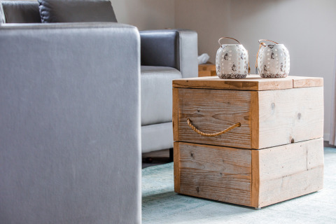 Modern lodge interior with a grey couch, a rustic wooden box table, and two white decorative jars.