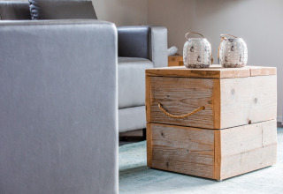 Modern lodge interior with a grey couch, a rustic wooden box table, and two white decorative jars.