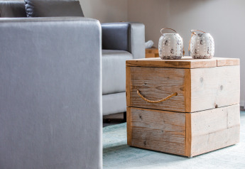 Interno di lodge moderno con divano grigio e tavolino in legno rustico decorato con due barattoli bianchi.