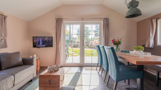 Licht interieur van een lodge op Vakantiepark Leukermeer met moderne meubels en zicht op de tuin.