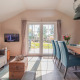 Helles Wohnzimmer in einer Lodge im Vakantiepark Leukermeer mit Holztisch, Sofa und Gartenausblick.