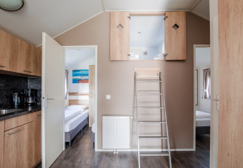 Lodge moderno con altillo abierto, dos dormitorios, cocina y escalera en Vakantiepark Leukermeer, Países Bajos.